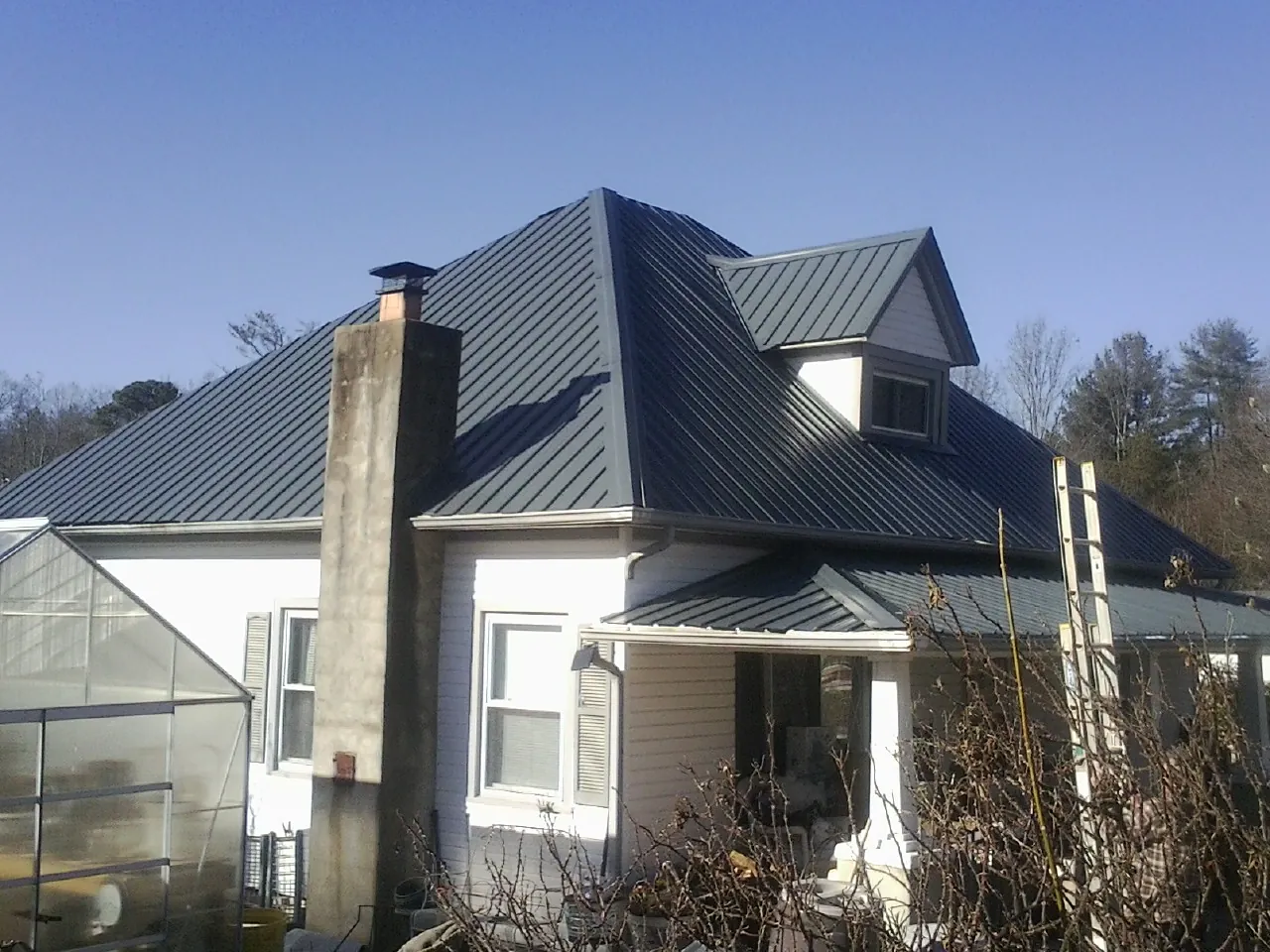 Dark blue standing seam metal roof on a white farmhouse with dormer — Slate & Tile Roof Repair by Roofing Brothers in Discovery Bay
