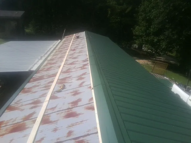 Old rusted panels beside newly installed green metal roofing — Wind Damage Roof Repair by Roofing Brothers in Discovery Bay