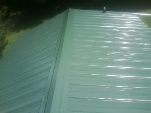 New green metal panels meeting at the ridge of a roof — Flat Roof Repair work by our crew in Discovery Bay