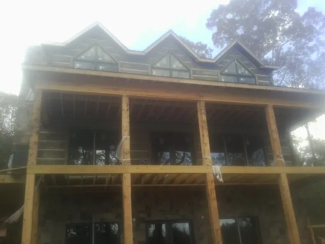 Dormers and porch framing on a large log home under construction — Roof Coating work by our crew in Discovery Bay