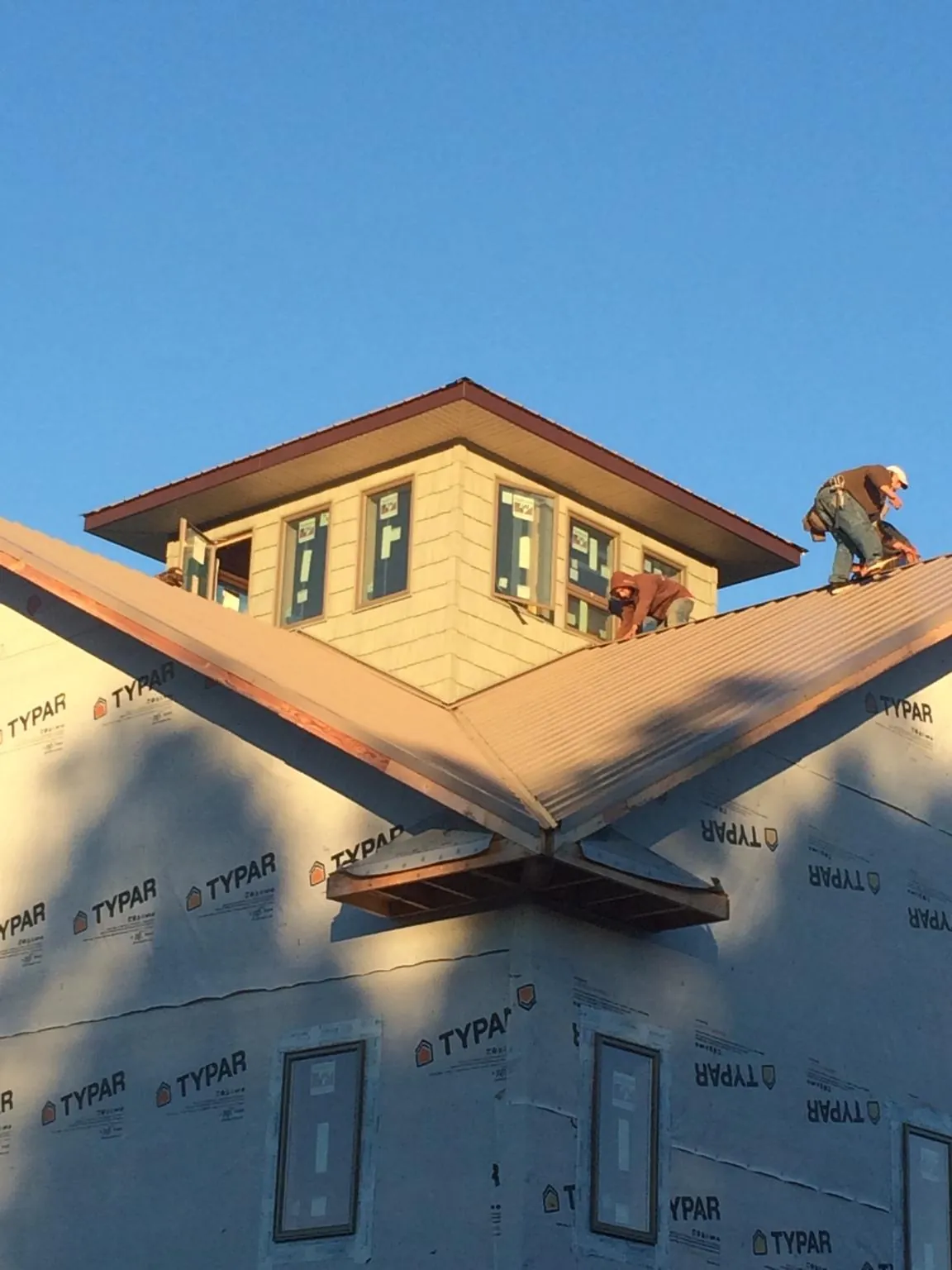 Roofers working around a rooftop cupola on a new metal roof at sunset — Roof Waterproofing in Discovery Bay by Roofing Brothers